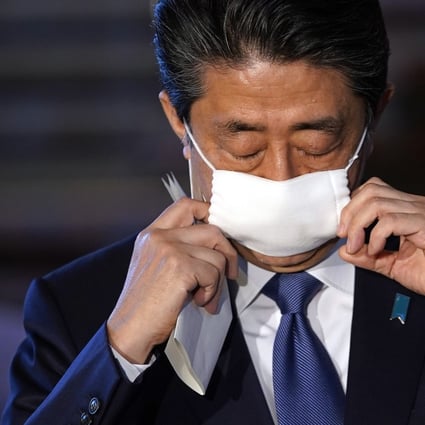 Japanese Prime Minister Shinzo Abe takes off his face mask as he arrives for a press conference at the prime minister's official residence in Tokyo on April 6, 2020. Japan is declaring a state of emergency for parts of the country and planning a huge near-US$1 trillion stimulus for households and businesses due to the virus. Photo: EPA-EFE