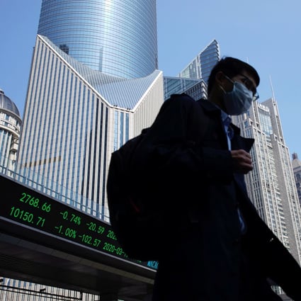 A pedestrian wearing a face mask walks near an overpass with an electronic board showing information on Shanghai stock exchange. Photo: Reuters
