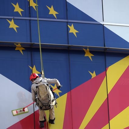 Workers clean the windows of the offices of the European Union decorated with EU and Macedonian flags in Skopje, North Macedonia, in February 2019. Photo: EPA-EFE