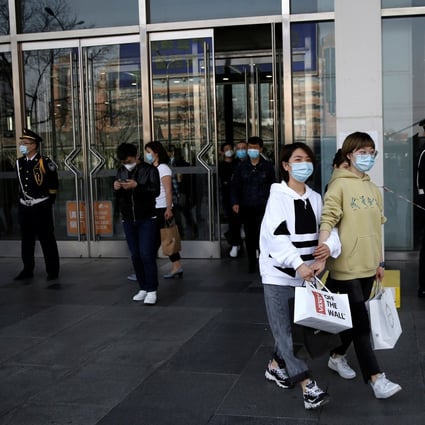 Shoppers with face masks walking out of a mall in Beijing as the pandemic shrinks the nation’s much-vaunted army of consumers. Photo: Reuters