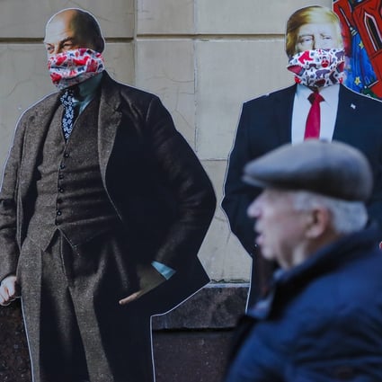 A man passes cardboard figures of Soviet Union founder Vladimir Lenin, US President Donald Trump and Chinese President Xi Jinping wearing face masks near a souvenir shop in Moscow. The three countries will be instrumental in shaping the post-coronavirus world. Photo: EPA-EFE