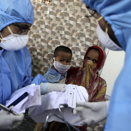Doctors check people for coronavirus symptoms in a slum area of Mumbai during India’s nationwide lockdown. Photo: AP