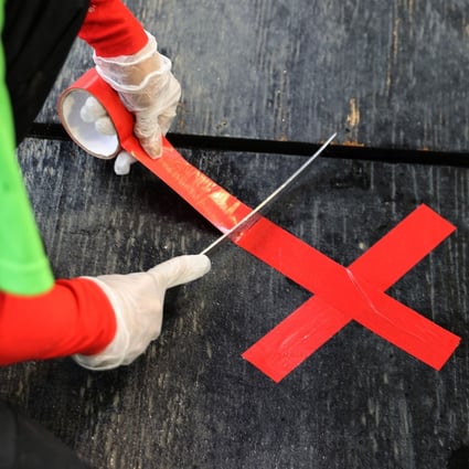 An employee marks spots to remind customers to maintain social distancing at Captain Whites Seafood City in the reopened Municipal Fish Market in Washington on Monday. Photo: AFP