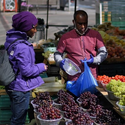 Customers buy fruit and vegetables from a stall at Whitechapel market in east London. Photo: AFP