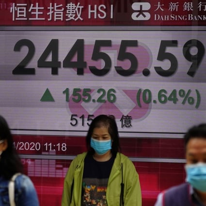 People wearing face masks walk past a bank electronic board showing the Hong Kong share index at Hong Kong Stock Exchange Tuesday, April 14, 2020. Asian shares rose Tuesday although investors were braced for a sobering first look at how the coronavirus pandemic has hurt global corporate earnings and the Chinese economy, the driver of growth for the region. (AP Photo/Vincent Yu)