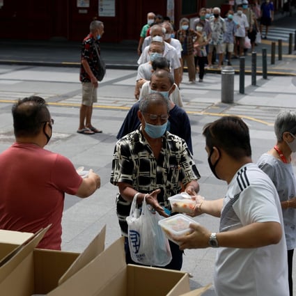 Owners of a Singapore restaurant distribute food to the elderly. Photo: Reuters