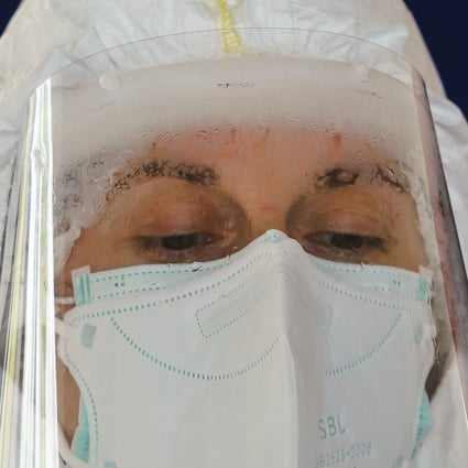 A health care worker in protective gear collects samples from drivers at a drive-through testing point in Spain. Photo: AFP