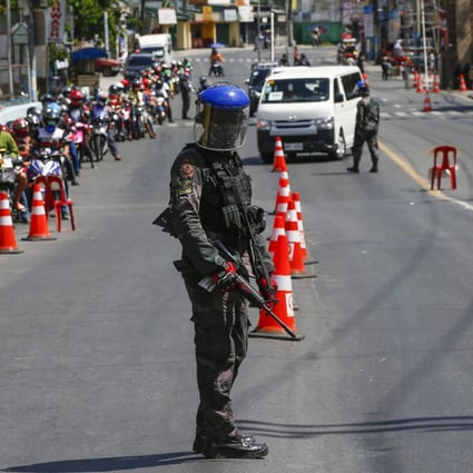 An armed police officer guards a checkpoint in Metro Manila earlier this month amid the antivirus lockdown of Luzon island. Photo: EPA