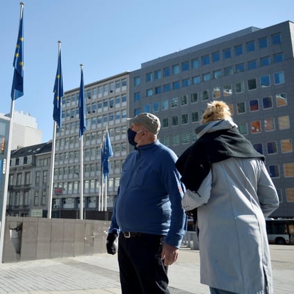 A couple wearing protective face masks walks past the European Commission headquarters in Brussels, Belgium, on April 23 amid the continued spread of the coronavirus across the continent. Photo: Reuters