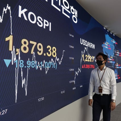 People wearing face masks look at an electronic signboard at the trading room of KB Kookmin Bank. Photo: YNA/DPA