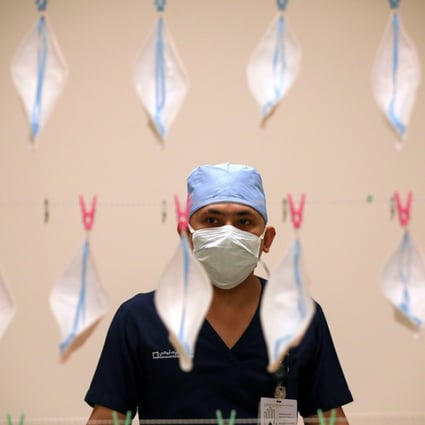 A technician hangs up face masks to be sterilised with UVC light. Photo: Reuters