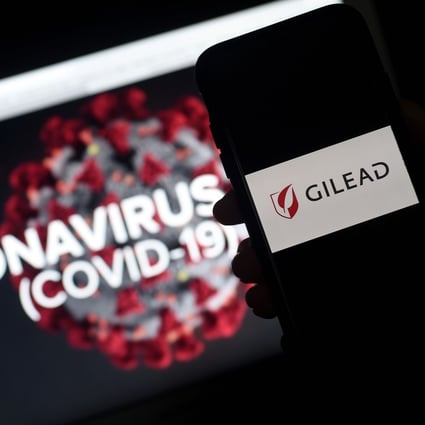 Gilead’s logo is displayed on a smartphone next to a screen showing a coronavirus graphic on March 25, 2020 in Arlington, Virginia. Photo: AFP