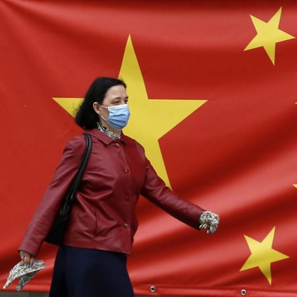A woman wearing a face mask walks by a Chinese flag on a street in Belgrade, Serbia on April 13. Photo: AP