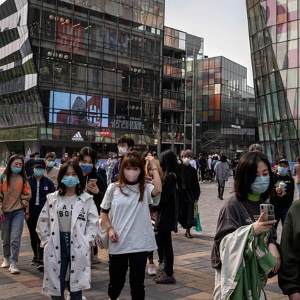 People wearing face masks amid concerns over the coronavirus walk past a shopping centre in Beijing. Governments around the world are unleashing trillions of dollars to keep businesses and workers afloat. Photo: AFP