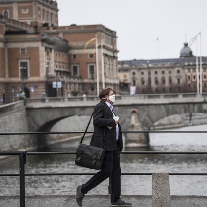 A man wearing a protective mask walks in the rain past the Royal Swedish Opera in Stockholm, Sweden on Monday. Photo: EPA-EFE