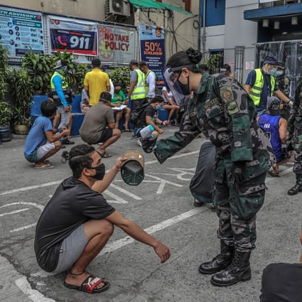 Members of the public, detained for roaming the streets without relevant passes amid the Covid-19 pandemic, are processed outside a police station in Manila, the Philippines. Photo: AFP