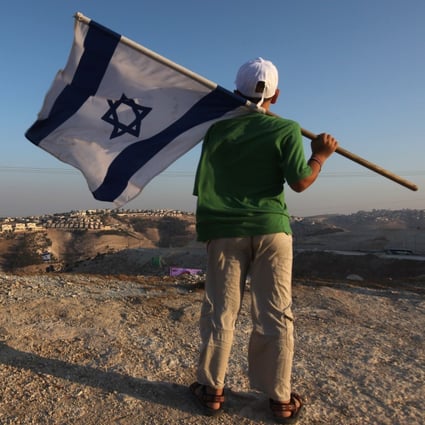 A right-wing supporter holds his national flag near the Jewish settlement of Maale Adumim, east of Jerusalem. File photo: AFP