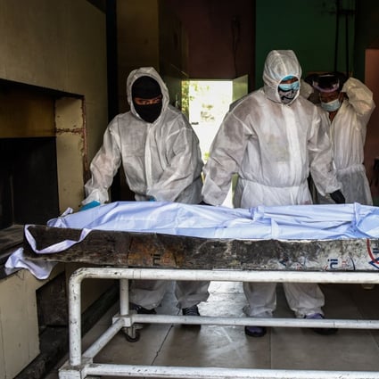 Personnel in protective suits prepare to move a body inside the crematory chambers at a crematorium facility in Manila. Photo: AFP