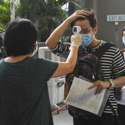 A school pupil has his temperature checked as he enters an exam hall for the Diploma of Secondary Education. Photo: Handout