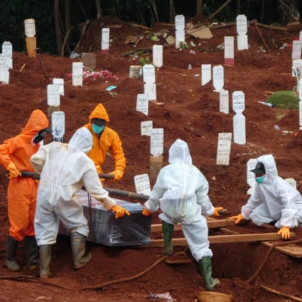 Workers move the coffin of a coronavirus victim at a cemetery in Jakarta. Photo: AFP