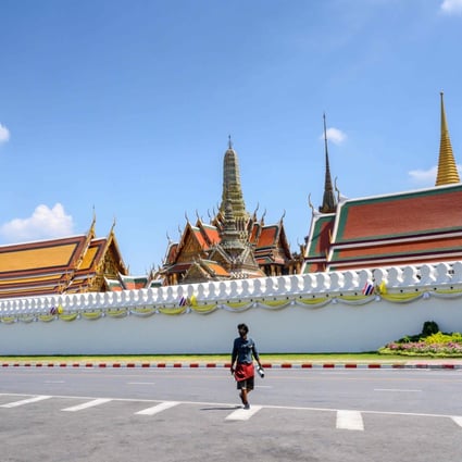 A man, wearing a facemask amid concerns about the spread of Covid-19, crosses a deserted street in front of the Grand Palace in Bangkok. Photo: AFP