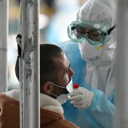 A medical worker, covered in protective clothing, takes coronavirus test samples. South Korean officials have concluded that those who test positive twice are most probably returning “false positive” results. Photo: AFP