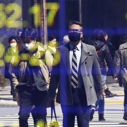 People are reflected on the electronic board of a securities firm in Tokyo. Photo: AP