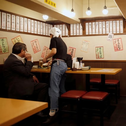 A Tokyo office worker is seen at a discount izakaya bar offering cheap food and drinks. Some establishments were targeted before Japan lifted its emergency restrictions. Photo: Reuters