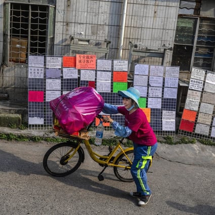A woman walks by a message boards filled with ads for jobs, flats to rent and business services in Little Hubei village of Guangzhou, Guangdong province. Photo: EPA-EFE