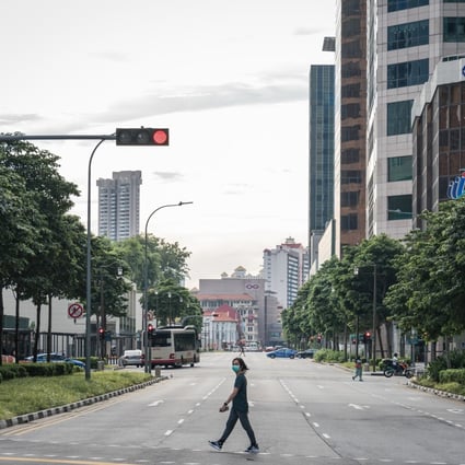 A pedestrian wearing a mask crosses a near-empty street in the central business district during the “circuit breaker” lockdown in Singapore on May 20. Singapore will allow more businesses to reopen on June 2 after a nationwide lockdown cut transmission of the coronavirus among citizens and permanent residents. Photo: Bloomberg