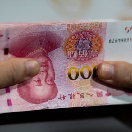A bank employee counts 100-yuan notes at a bank in Shanghai. Photo: AFP