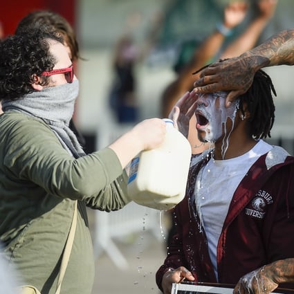 Protesters use milk to clear their eyes after being tear gassed by police in Minneapolis. Photo: EPA-EFE