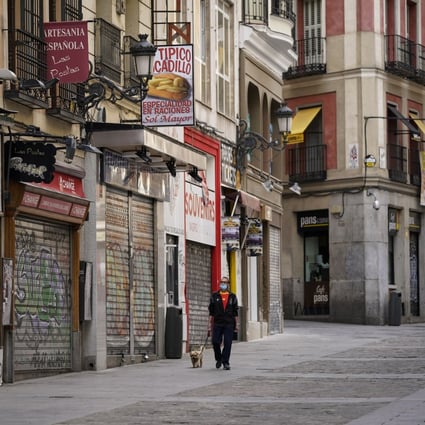 A man walks his dog along a street lined with closed cafes and stores in Madrid, Spain, on May 7. Italy and Spain, the two European countries most severely hit by the coronavirus, are suffering even deeper economic slumps after record contractions in the first quarter. Photo: Bloomberg