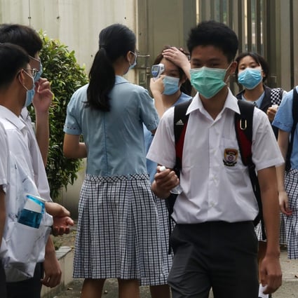 A student checks a peer’s temperature at the campus entrance, on the first day back to school after months of closure due to coronavirus-prevention measures, at a school in Shek Kip Mei on May 20. Photos: Jonathan Wong