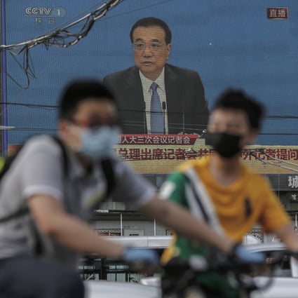 People ride their bicycles near a large screen showing a press conference by Chinese Premier Li Keqiang following the closing session of the 13th National People’s Congress in Beijing on May 28. Photo: EPA-EFE
