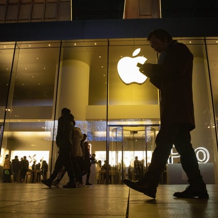 In this Dec. 13, 2019, file photo a man looks at his phone as he walks past a store of US tech giant Apple in a retail district in Beijing. Photo: AP