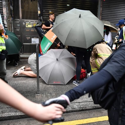Protesters form a human chain around a fellow protester receiving medical assistance after being struck by a vehicle. Photo: AFP