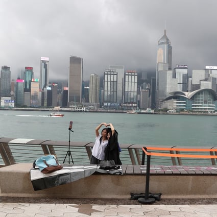 Two friends pose for graduation photos at the Tsim Sha Tsui waterfront promenade, with the Hong Kong Island skyline in the background, on June 8. Photo: Edmond So