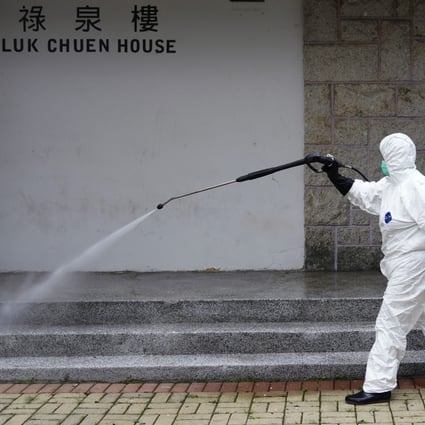 A worker in full protective gear disinfects Luk Chuen House at Lek Yuen Estate in Sha Tin. Photo: Sam Tsang