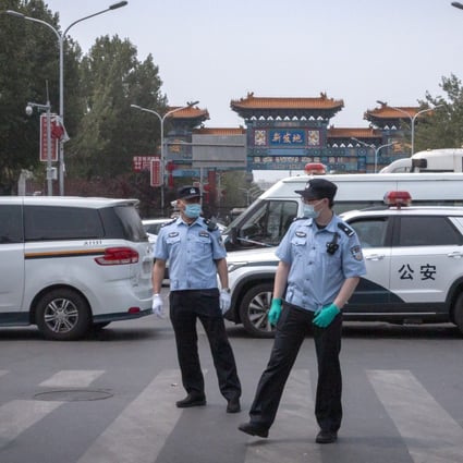 Police stand guard outside an entrance to the Xinfadi wholesale market district in Beijing on Saturday. Photo: AP