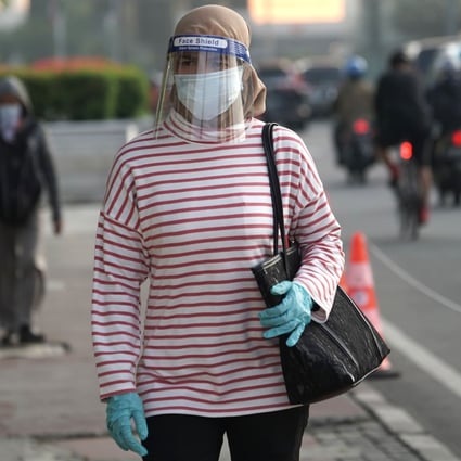 An Indonesian commuter, wearing a protective mask, gloves and face shield, is pictured in Jakarta before returning to work. The country is easing its partial lockdown and reopening the economy, but coronavirus cases are still on the rise. Photo: Bloomberg