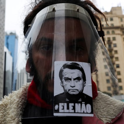 A man wears a protective face shield with a sticker of the image of Brazil’s President Jair Bolsonaro reading “not him” during a protest against racism and fascism in Sao Paulo. Photo: Reuters