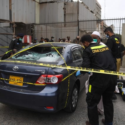 Police investigate a car thought to have been used by the gunmen at the main entrance of the Pakistan Stock Exchange building in Karachi on June 29. Photo: AFP