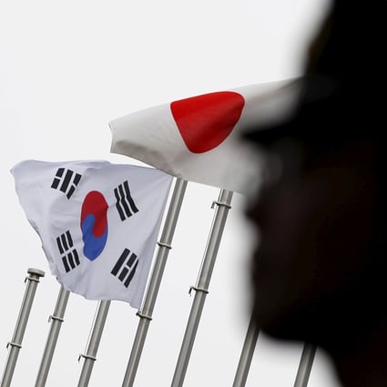 A police officer stands guard near Japanese and South Korean national flags during a 2015 reception to mark the normalising of ties between the two countries. Photo: Reuters