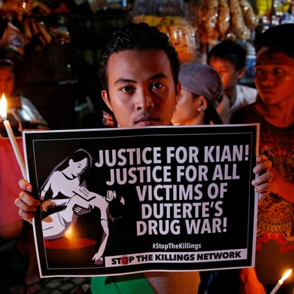 Protesters and residents hold lighted candles and placards at the wake of Kian delos Santos, a 17-year-old high school student who was among the minors killed by authorities. Photo: Reuters
