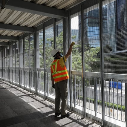 A worker checks the fence on a footbridge leading to the Legislative Council Complex in Tamar. Photo: Dickson Lee