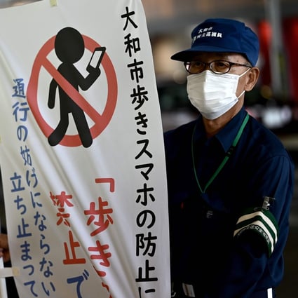 A city hall employee holds a banner to inform people about a ban on using mobile phones while walking. Photo: AFP