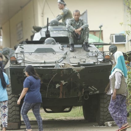 Villagers walk next to a tank in Jolo, in the Philippines, in March 2017. Photo: EPA