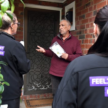Health workers speak to a resident of the Melbourne suburb of Brunswick West as they encourage people to take coronavirus tests. Photo: AFP
