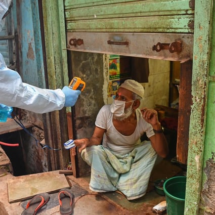 Medical staff wearing personal protective equipment take the temperature of a man as they conduct door-to-door Covid-19 screening inside the Dharavi slum in Mumbai. Photo: AFP